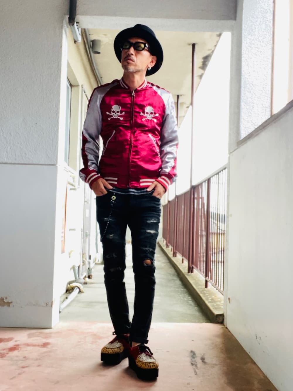 レッド系のスカジャン、ブラック系のタンクトップ、ブラック系のデニムパンツを着用したメンズの秋コーディネートの5枚目の写真