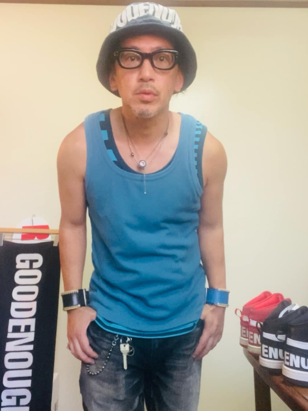 ブルー系のタンクトップ、ブラック系のデニムパンツ、ブラック系のスニーカーを着用したメンズの夏コーディネートの2枚目の写真