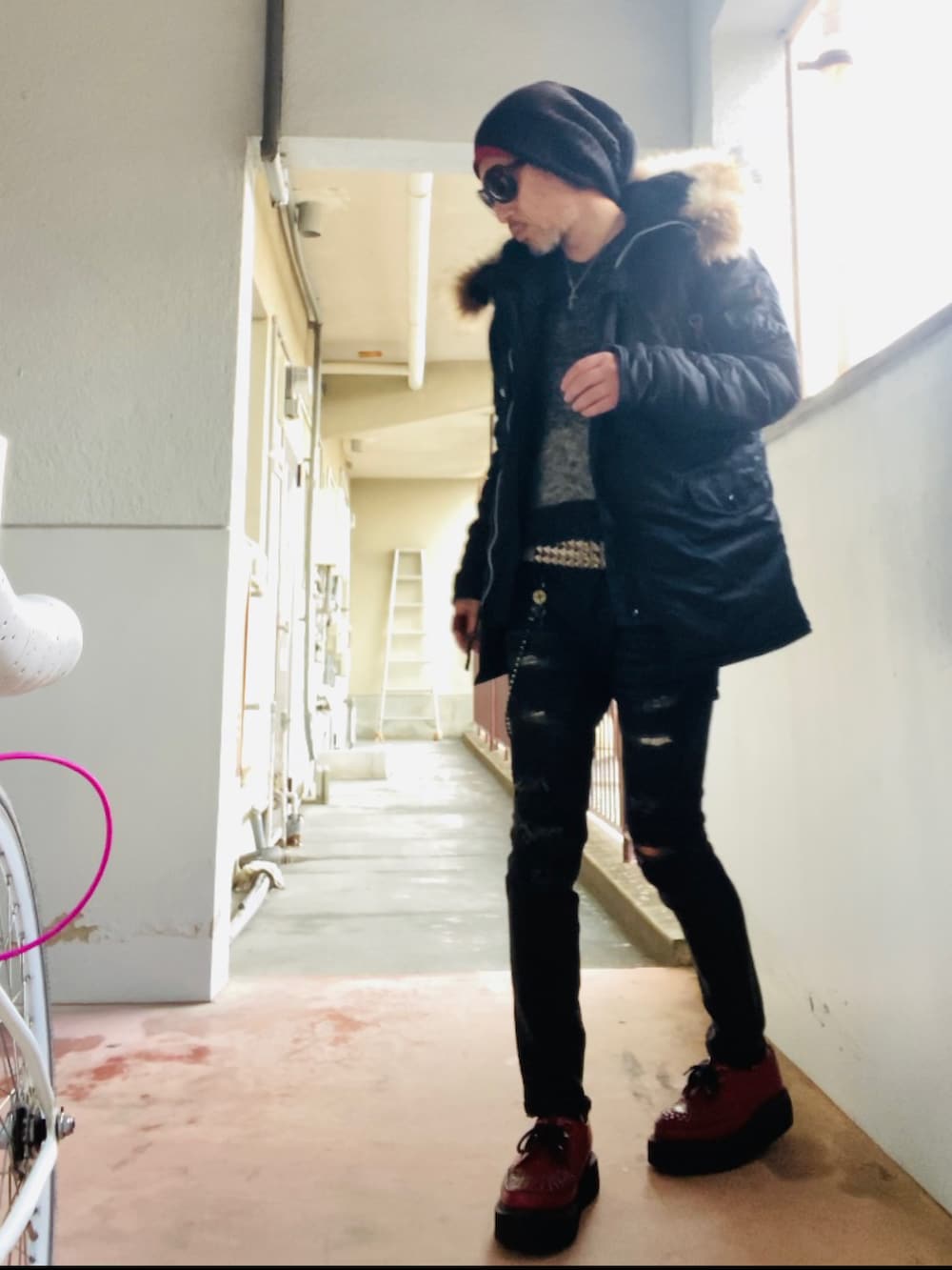 ブラック系のミリタリージャケット、ブラック系のニット/セーター、ブラック系のデニムパンツを着用したメンズの冬コーディネートの4枚目の写真