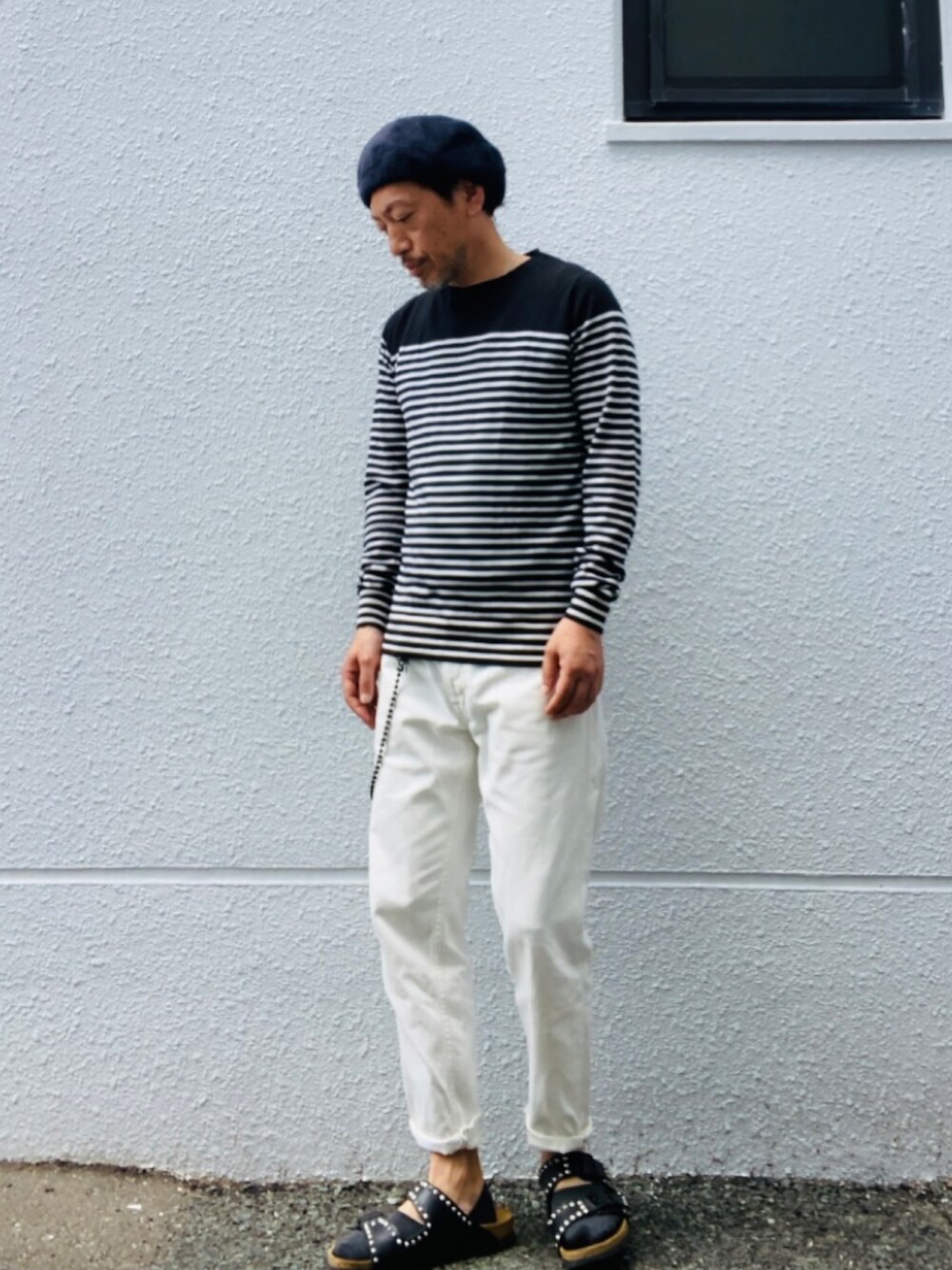 ブラック系のニット/セーター、ホワイト系のデニムパンツ、ブラック系のサンダルを着用したメンズの夏コーディネートの4枚目の写真