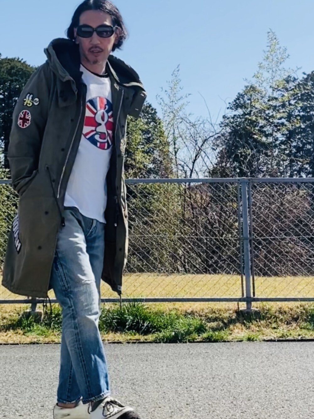 グリーン系のモッズコート、ホワイト系のTシャツ/カットソー、ブルー系のデニムパンツを着用したメンズの秋コーディネートの4枚目の写真