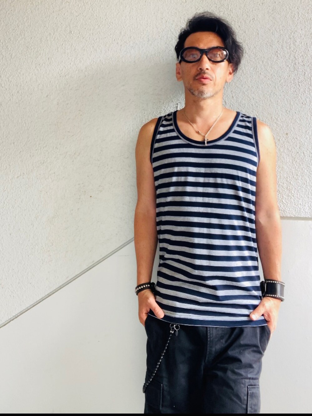 グレー系のタンクトップ、ブラック系のカーゴパンツ、ブラック系のサンダルを着用したメンズの夏コーディネートの2枚目の写真