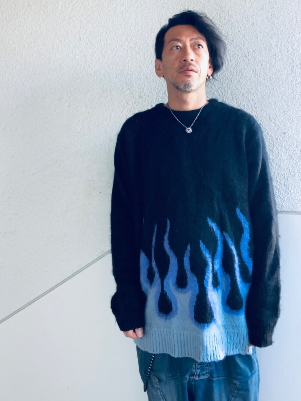 ブラック系のニット/セーター、ブルー系のデニムパンツ、ブラック系のスニーカーを着用したメンズの秋コーディネートの2枚目の写真