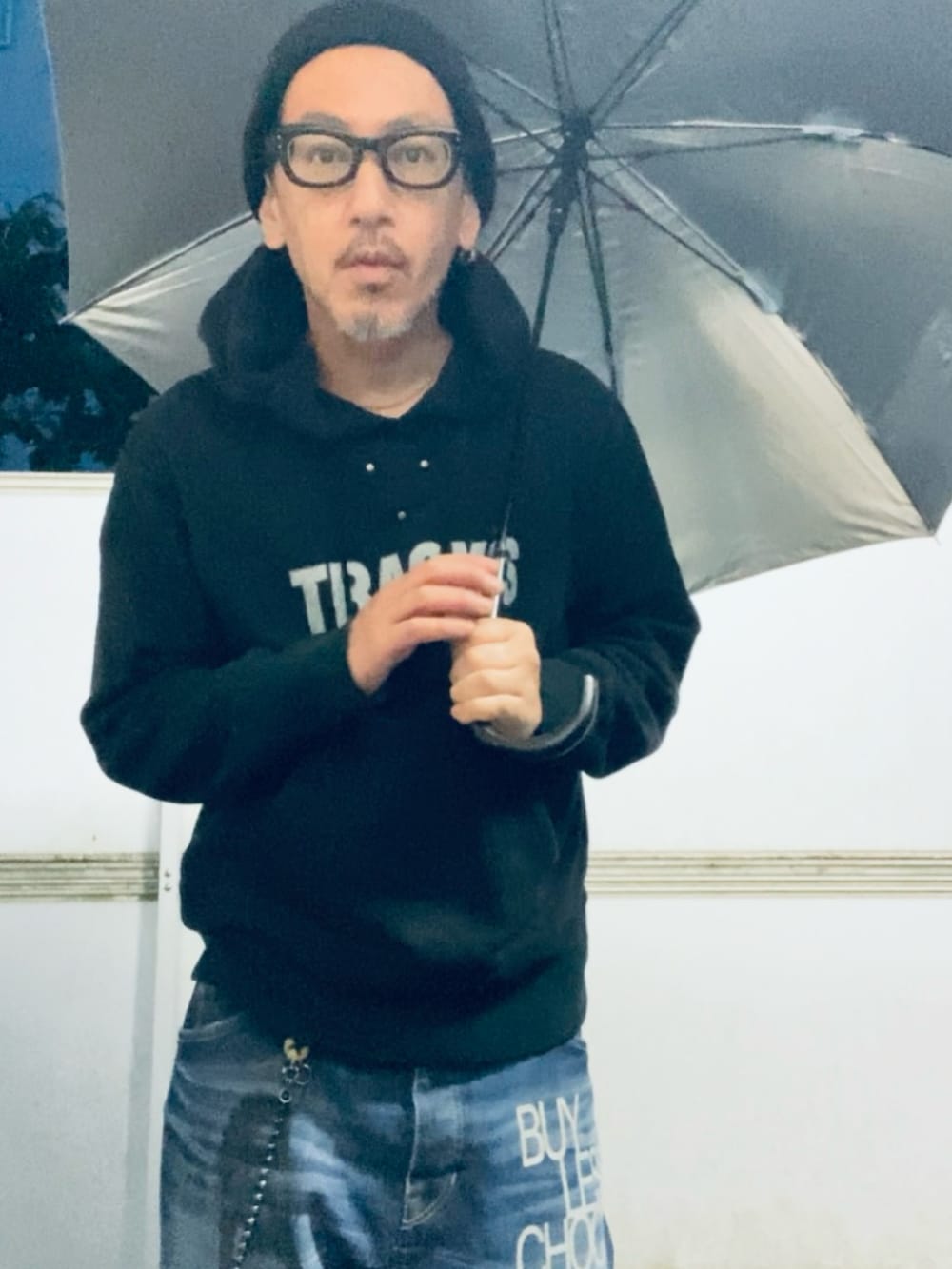 ブラック系のパーカー、ブルー系のデニムパンツ、ブラック系のスニーカーを着用したメンズの春コーディネートの2枚目の写真