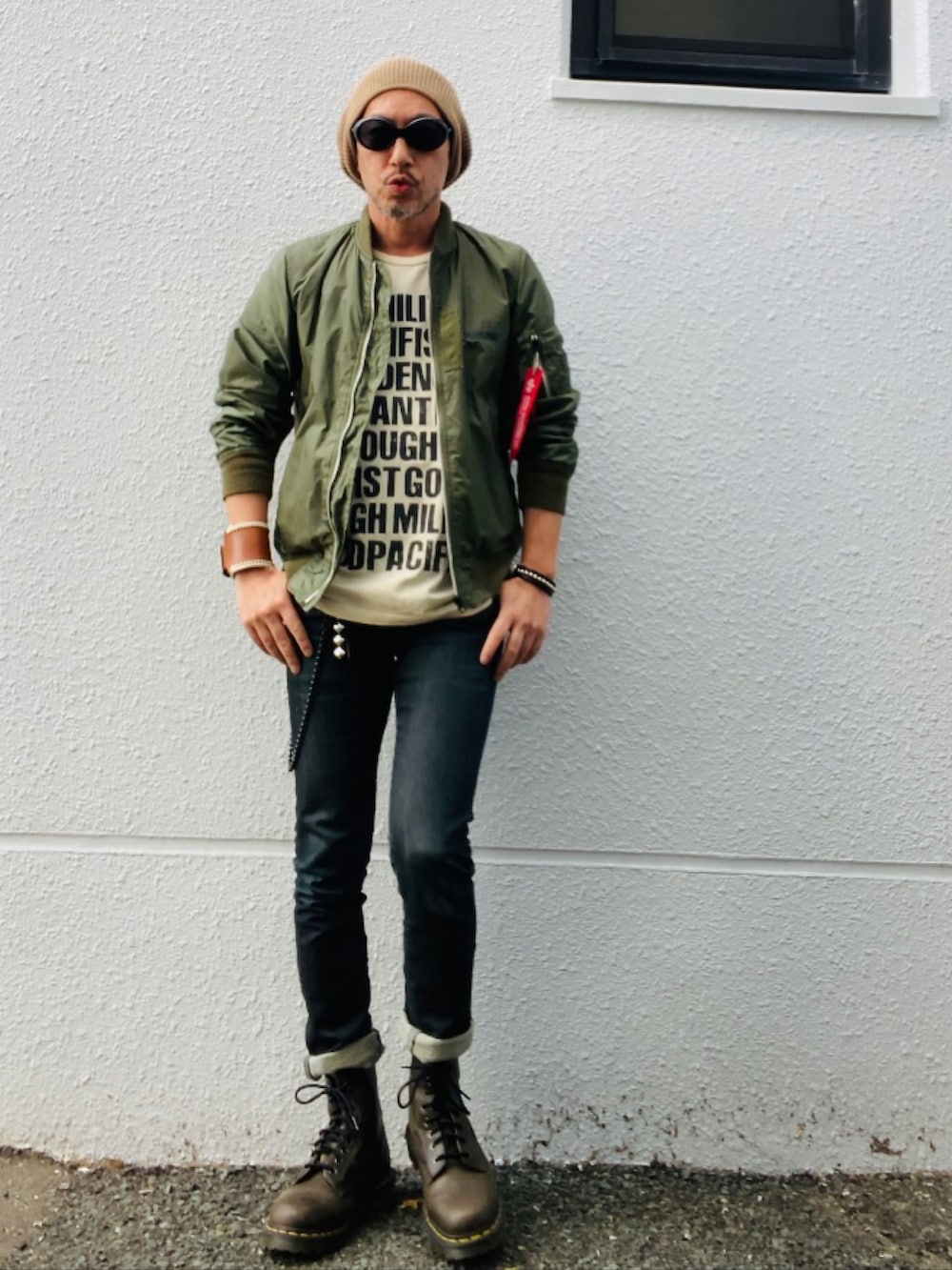 グリーン系のMA-1、ベージュ系のTシャツ/カットソー、ブラック系のデニムパンツを着用したメンズの春コーディネートの3枚目の写真