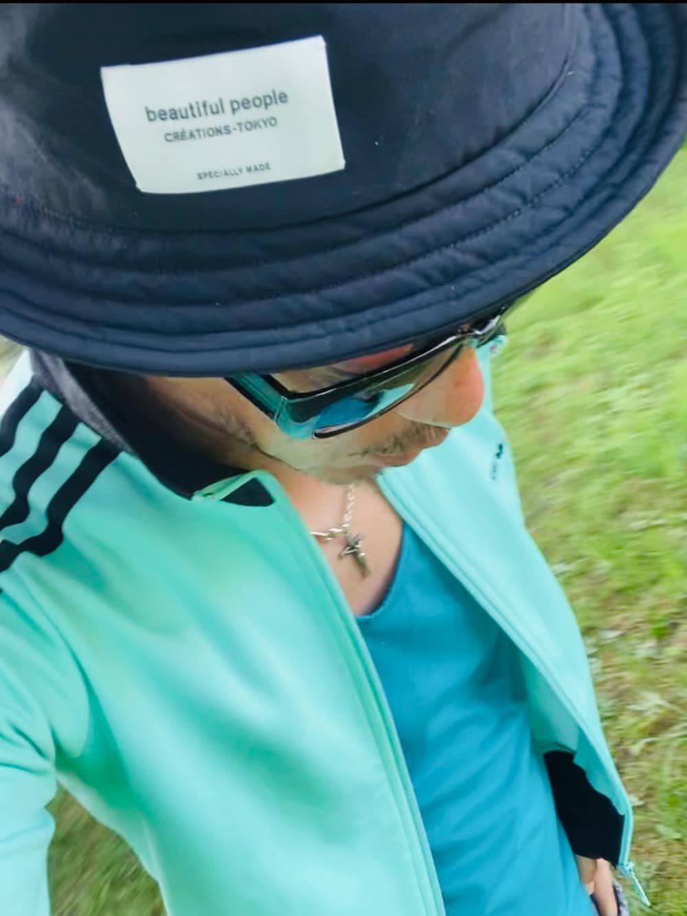 グリーン系のジャージ、ブルー系のタンクトップ、ブルー系のその他パンツを着用したメンズの夏コーディネートの3枚目の写真