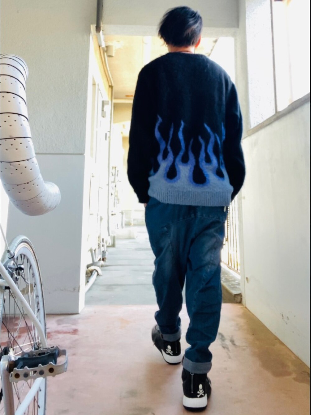 ブラック系のニット/セーター、ブルー系のデニムパンツ、ブラック系のスニーカーを着用したメンズの秋コーディネートの4枚目の写真