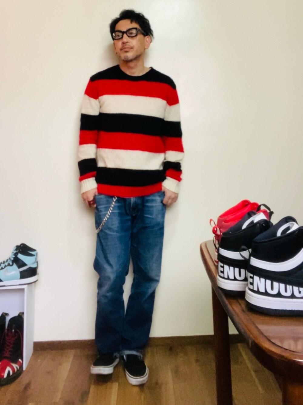 レッド系のニット/セーター、ブルー系のデニムパンツ、ブラック系のスリッポンを着用したメンズの春コーディネートの2枚目の写真