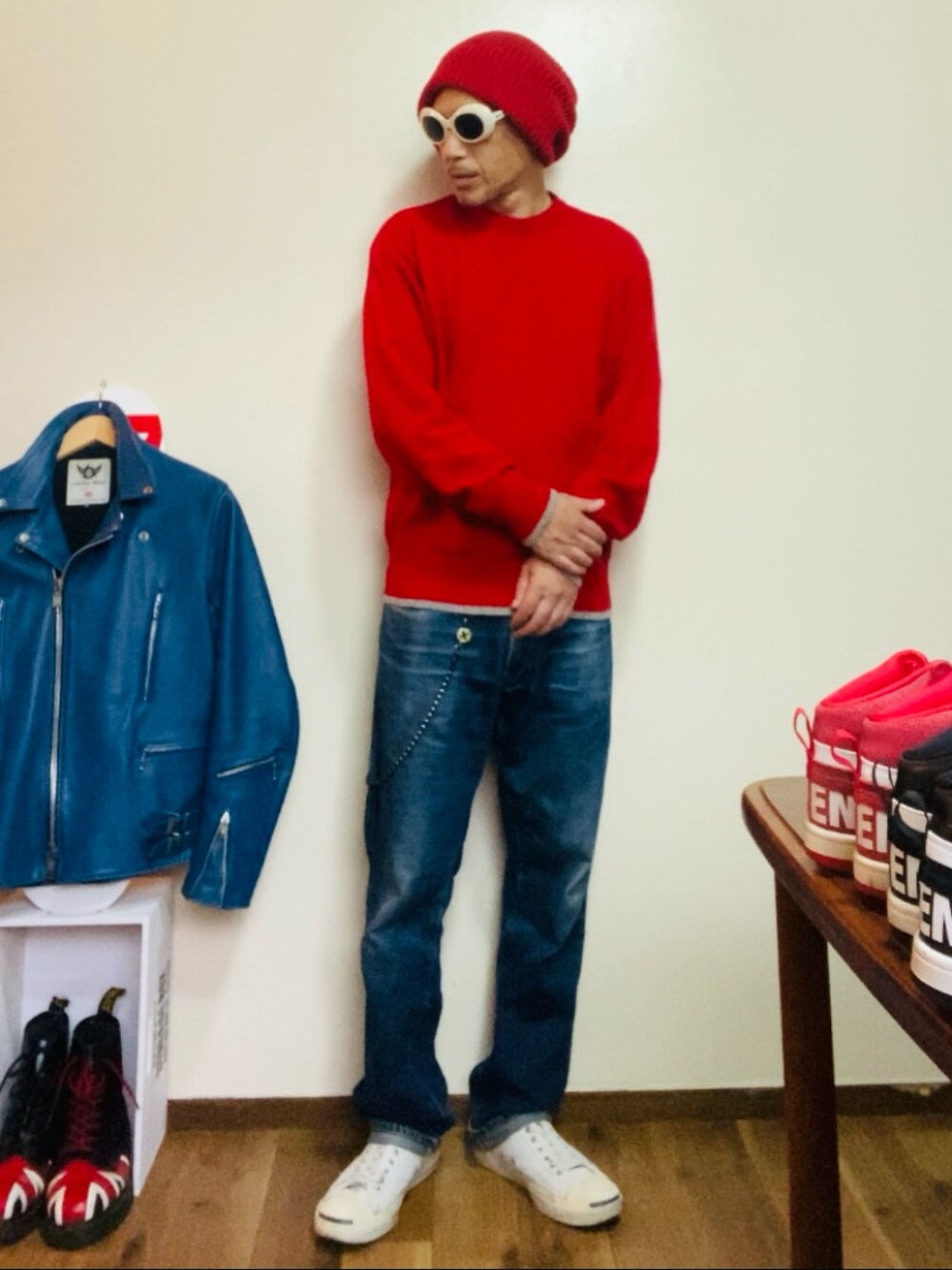 レッド系のニット/セーター、ブルー系のデニムパンツ、ホワイト系のスニーカーを着用したメンズの秋コーディネートの2枚目の写真