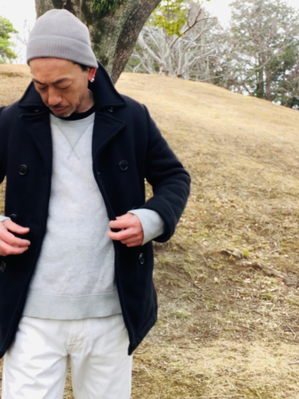 ブルー系のピーコート、グレー系のスウェット、ホワイト系のデニムパンツを着用したメンズの冬コーディネートの2枚目の写真