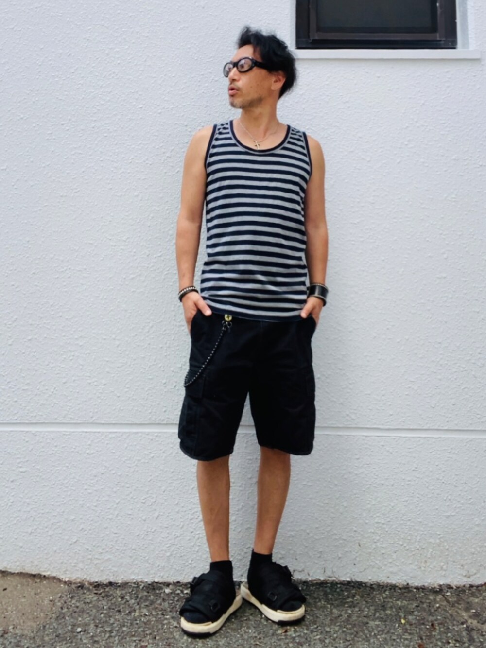 グレー系のタンクトップ、ブラック系のカーゴパンツ、ブラック系のサンダルを着用したメンズの夏コーディネートの3枚目の写真