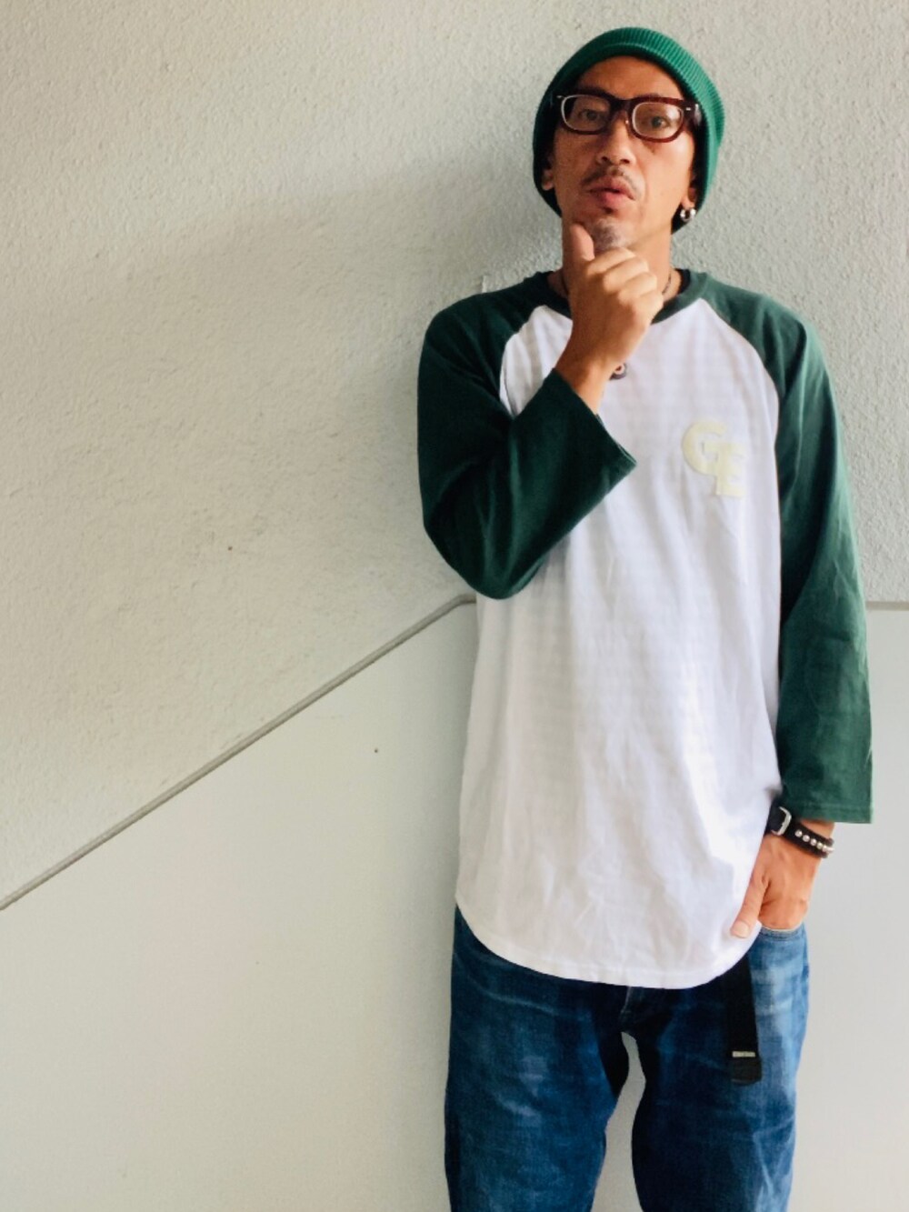 グリーン系のTシャツ/カットソー、ブルー系のデニムパンツ、グリーン系のスニーカーを着用したメンズの秋コーディネートの2枚目の写真
