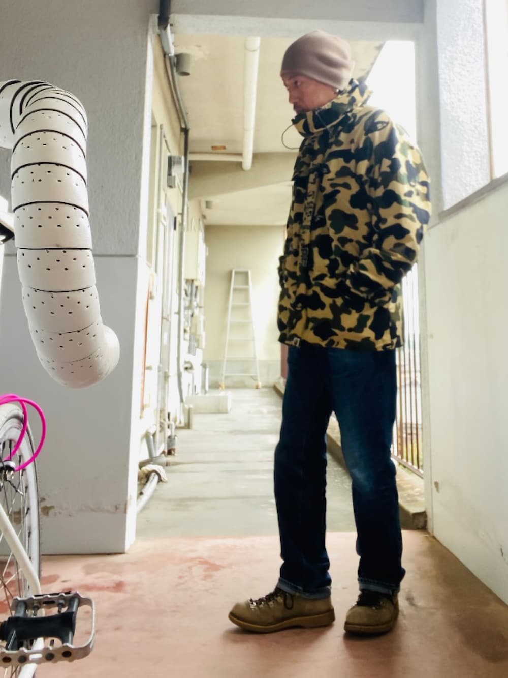 イエロー系のマウンテンパーカー、ブルー系のデニムパンツ、ベージュ系のブーツを着用したメンズの秋コーディネートの3枚目の写真