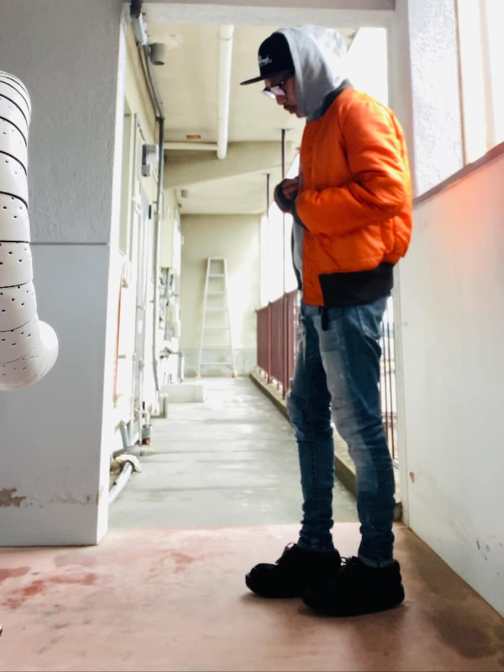 グレー系のパーカー、グレー系のMA-1、ブルー系のデニムパンツを着用したメンズの冬コーディネートの3枚目の写真