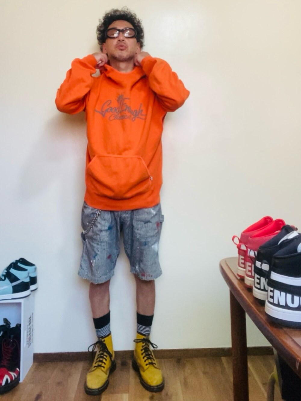 オレンジ系のパーカー、グレー系のデニムパンツ、イエロー系のブーツを着用したメンズの夏コーディネートの2枚目の写真