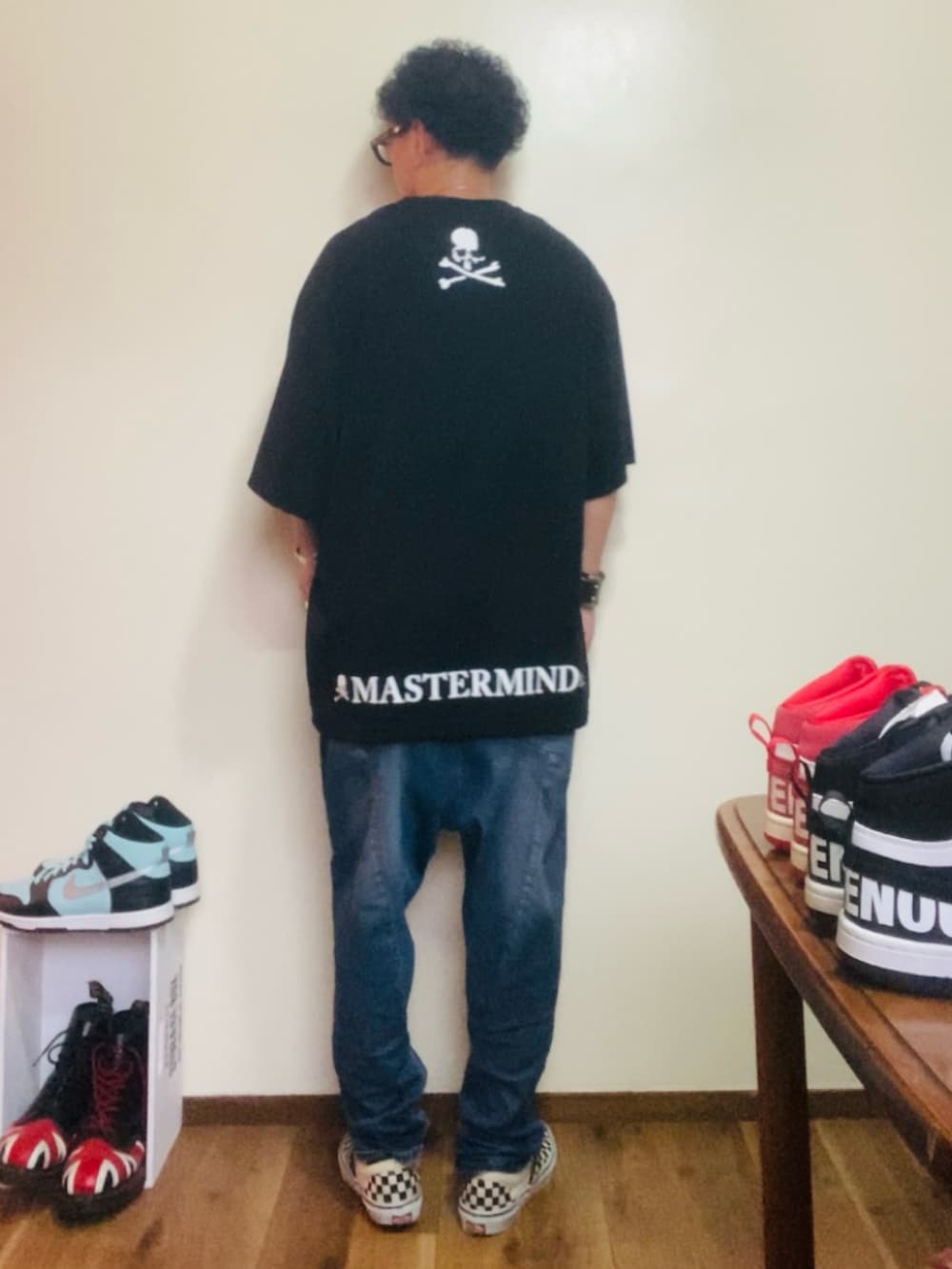 ブラック系のTシャツ/カットソー、ブルー系のデニムパンツ、ホワイト系のスリッポンを着用したメンズの夏コーディネートの4枚目の写真