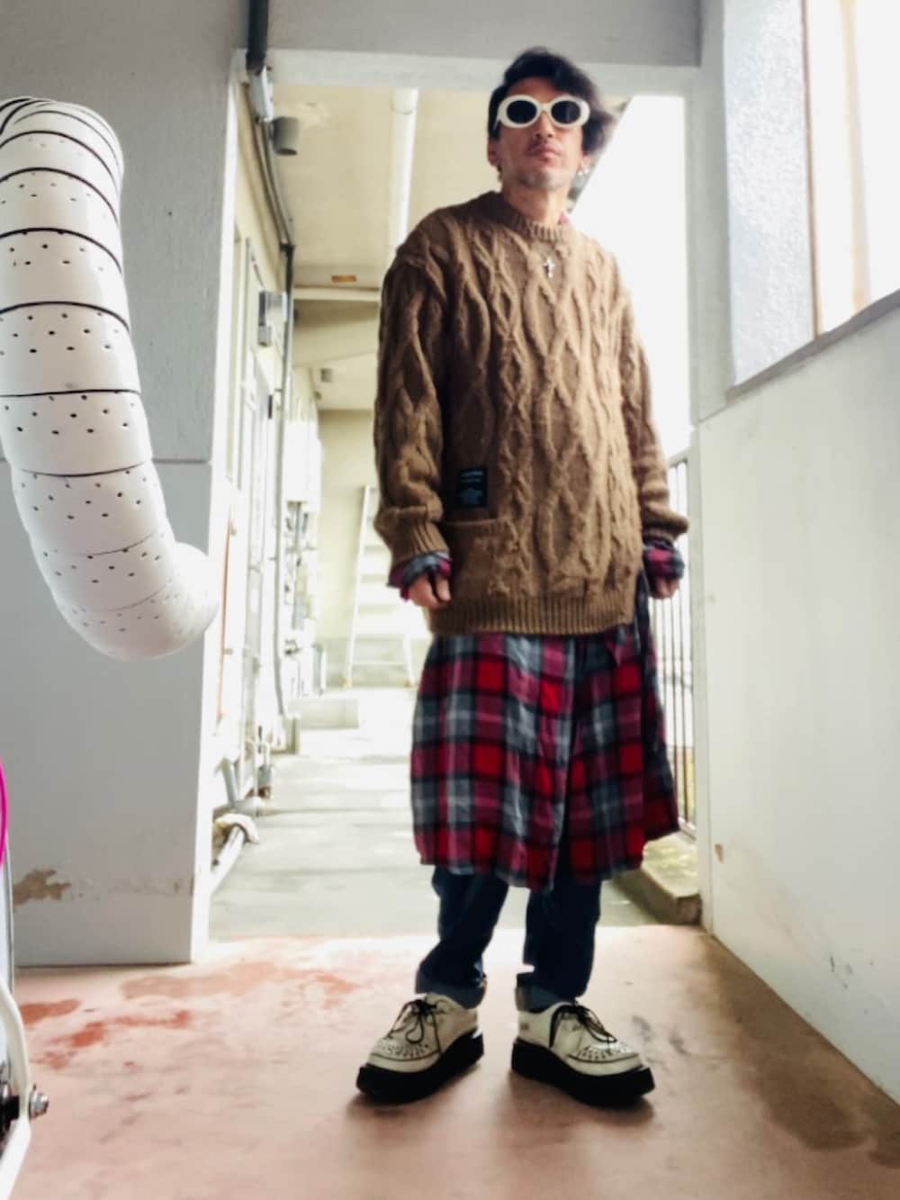 ブラウン系のニット/セーター、レッド系のノーカラーコート、ブルー系のデニムパンツを着用したメンズの秋コーディネートの3枚目の写真
