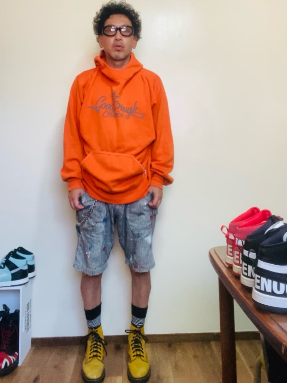 オレンジ系のパーカー、グレー系のデニムパンツ、イエロー系のブーツを着用したメンズの夏コーディネートの3枚目の写真