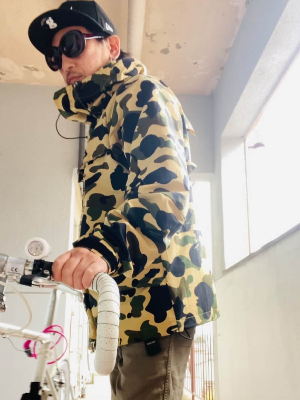 イエロー系のマウンテンパーカー、ブラウン系のチノパンツ、ブラック系のキャップを着用したメンズの秋コーディネートの4枚目の写真