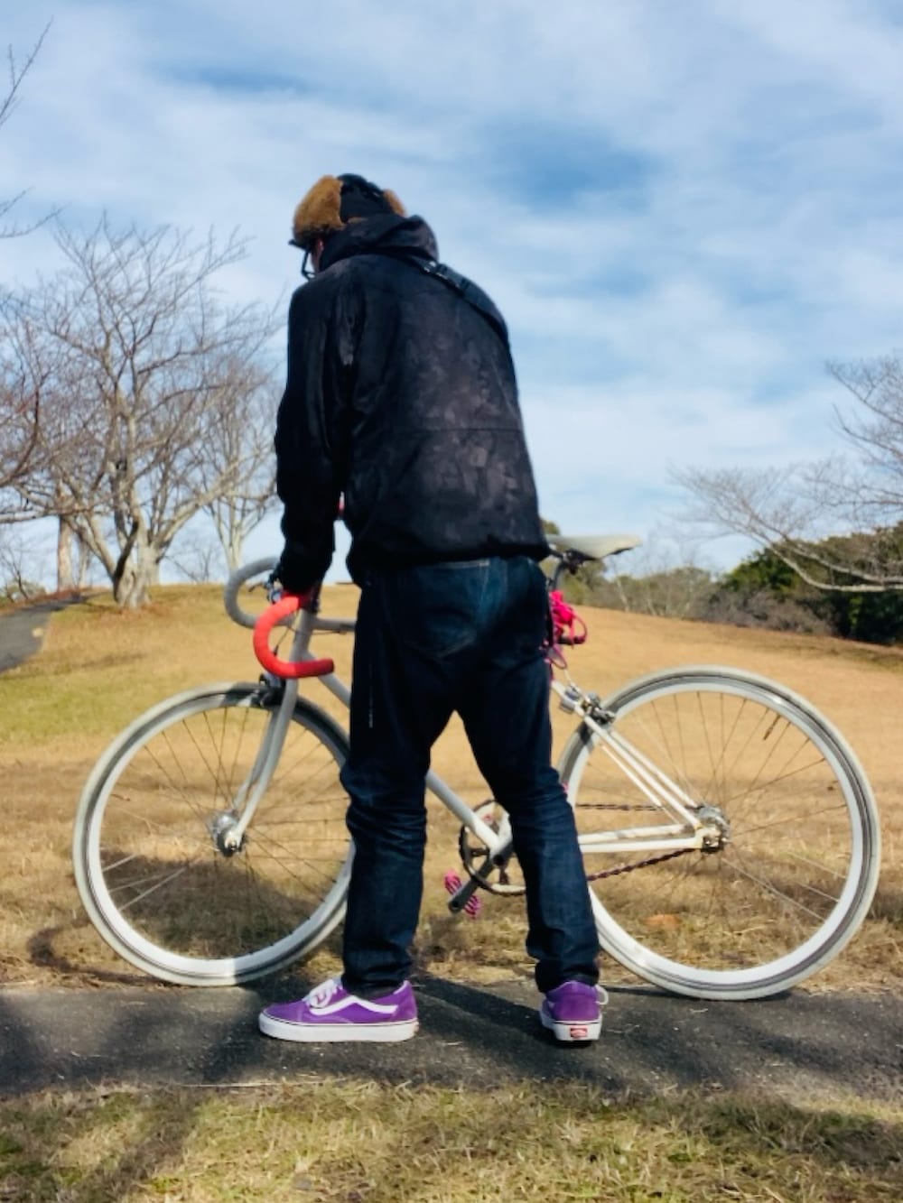 パープル系のスニーカー、ブラック系のマウンテンパーカー、ブルー系のデニムパンツを着用したメンズの冬コーディネートの2枚目の写真