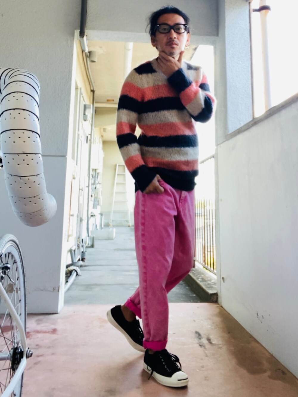 ピンク系のニット/セーター、ピンク系のデニムパンツ、ブラック系のスニーカーを着用したメンズの秋コーディネートの4枚目の写真