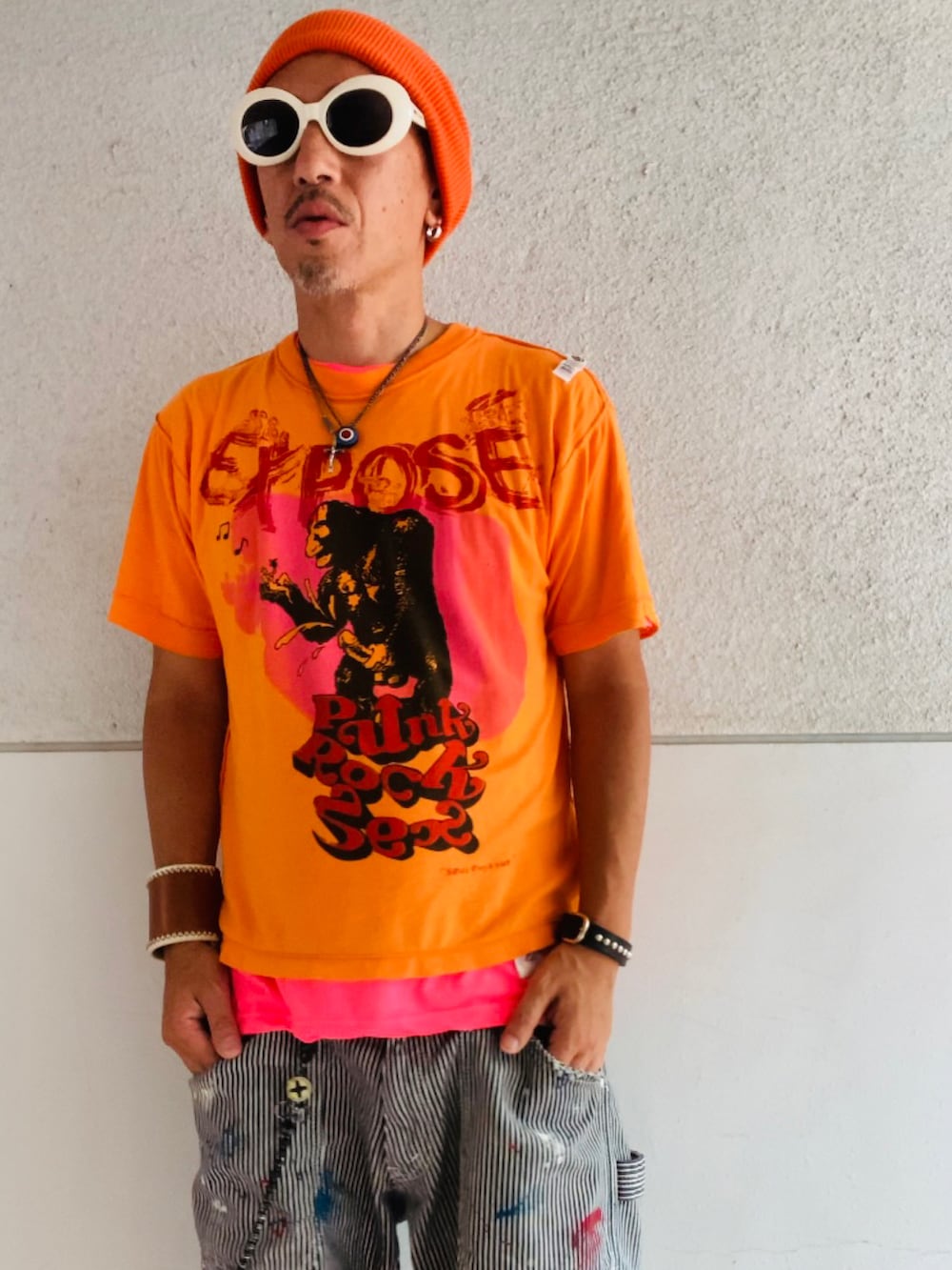 オレンジ系のTシャツ/カットソー、ピンク系のTシャツ/カットソー、グレー系のデニムパンツを着用したメンズの秋コーディネートの2枚目の写真