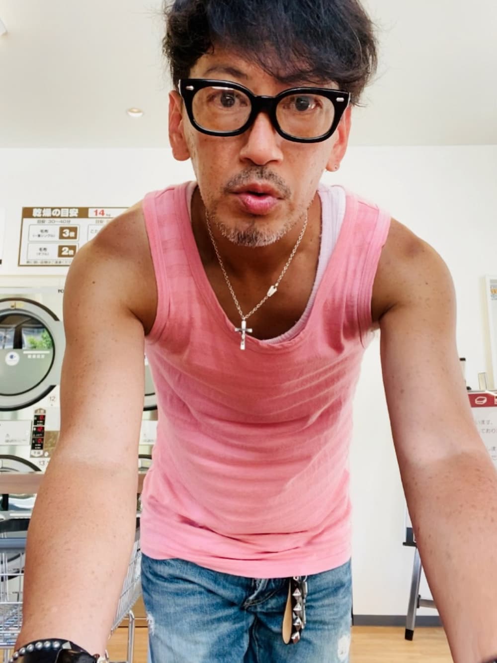 ピンク系のタンクトップ、ブルー系のデニムパンツ、ピンク系のスニーカーを着用したメンズの夏コーディネートの2枚目の写真