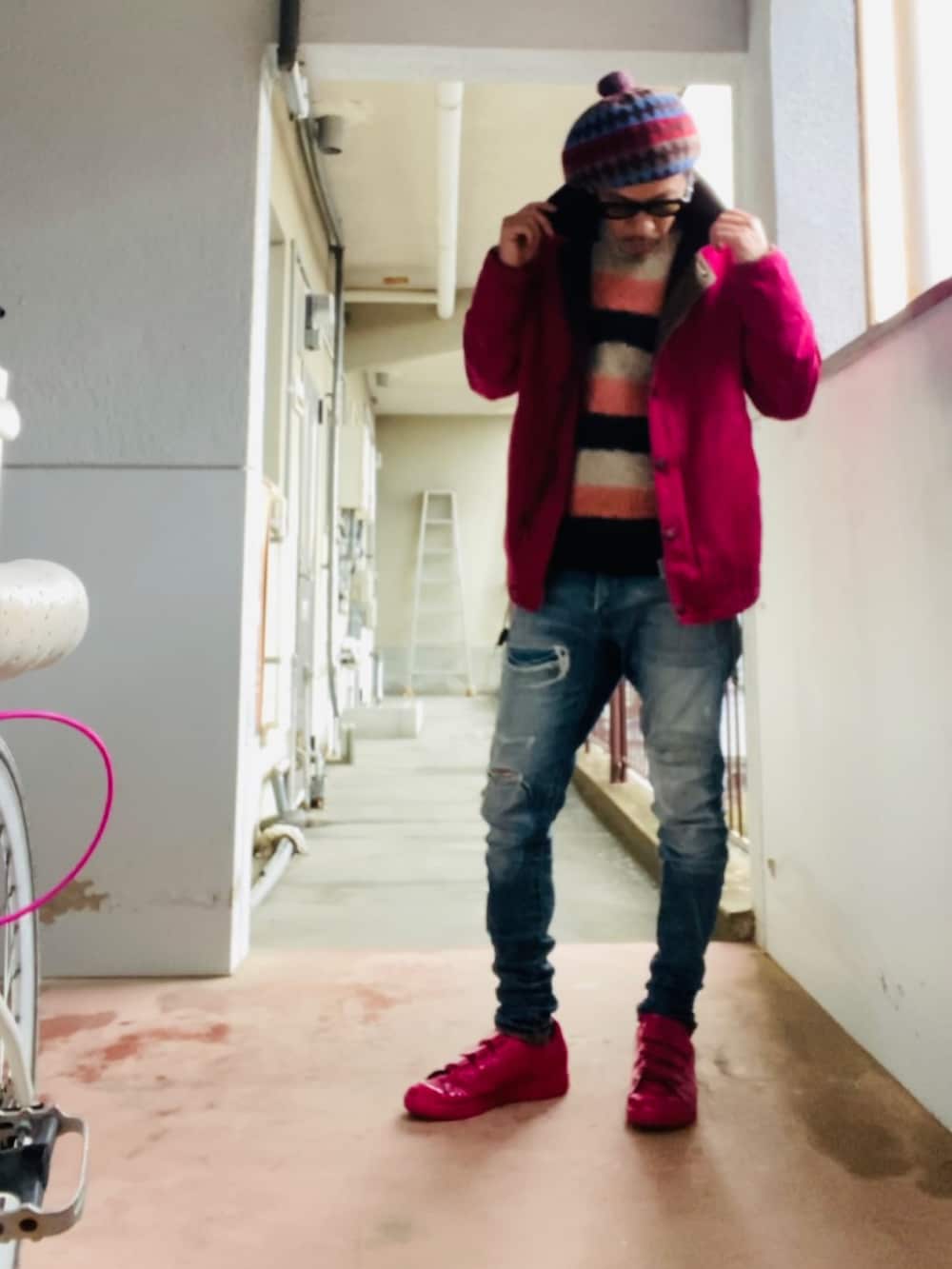 ピンク系のニット/セーター、ピンク系のミリタリージャケット、ブルー系のデニムパンツを着用したメンズの冬コーディネートの5枚目の写真