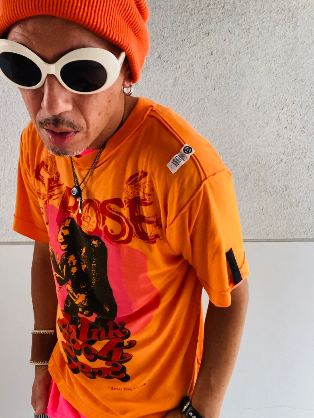 オレンジ系のTシャツ/カットソー、ピンク系のTシャツ/カットソー、グレー系のデニムパンツを着用したメンズの秋コーディネートの4枚目の写真