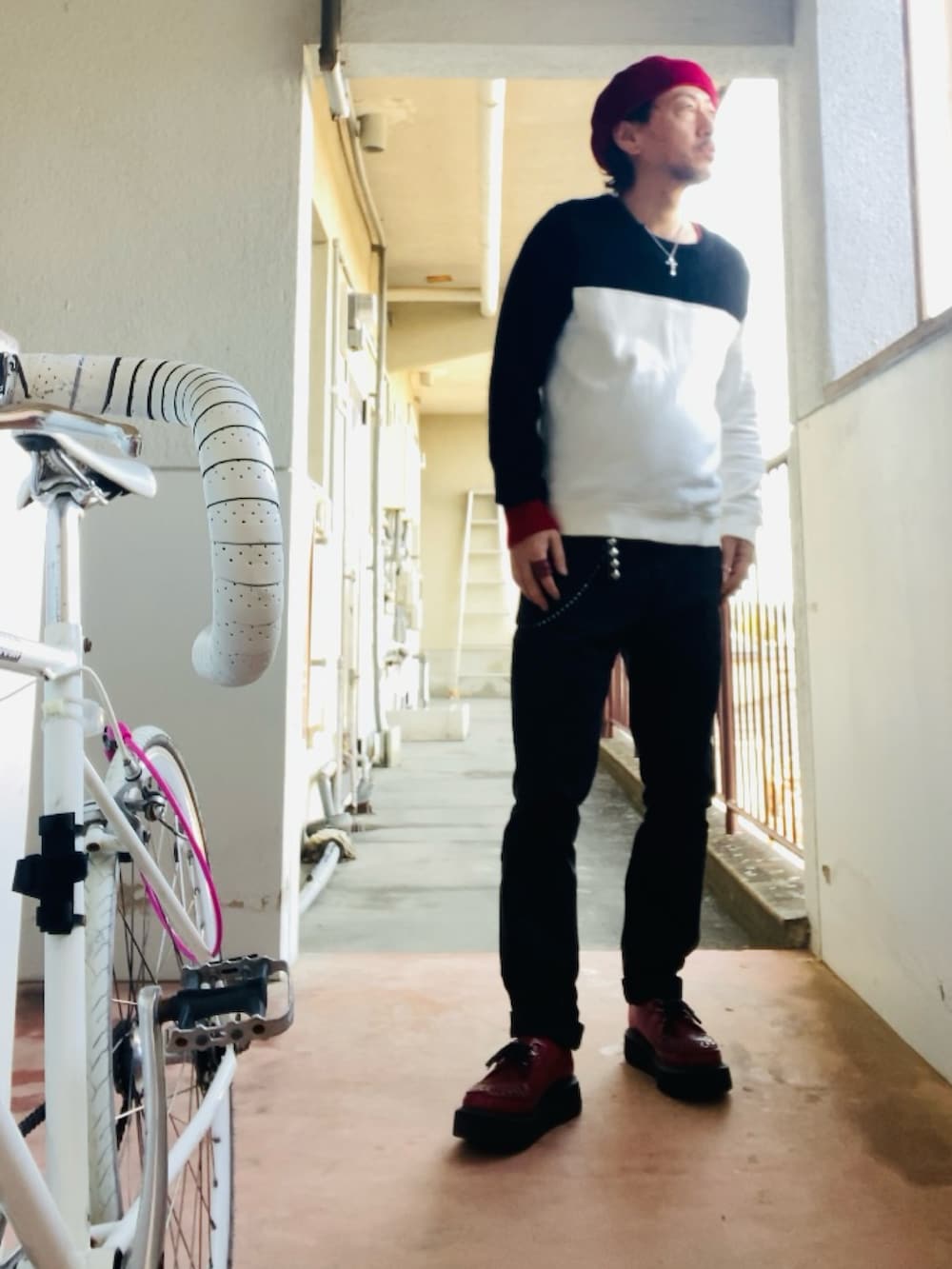 ブラック系のニット/セーター、ブラック系のチノパンツ、レッド系のブーツを着用したメンズの春コーディネートの4枚目の写真