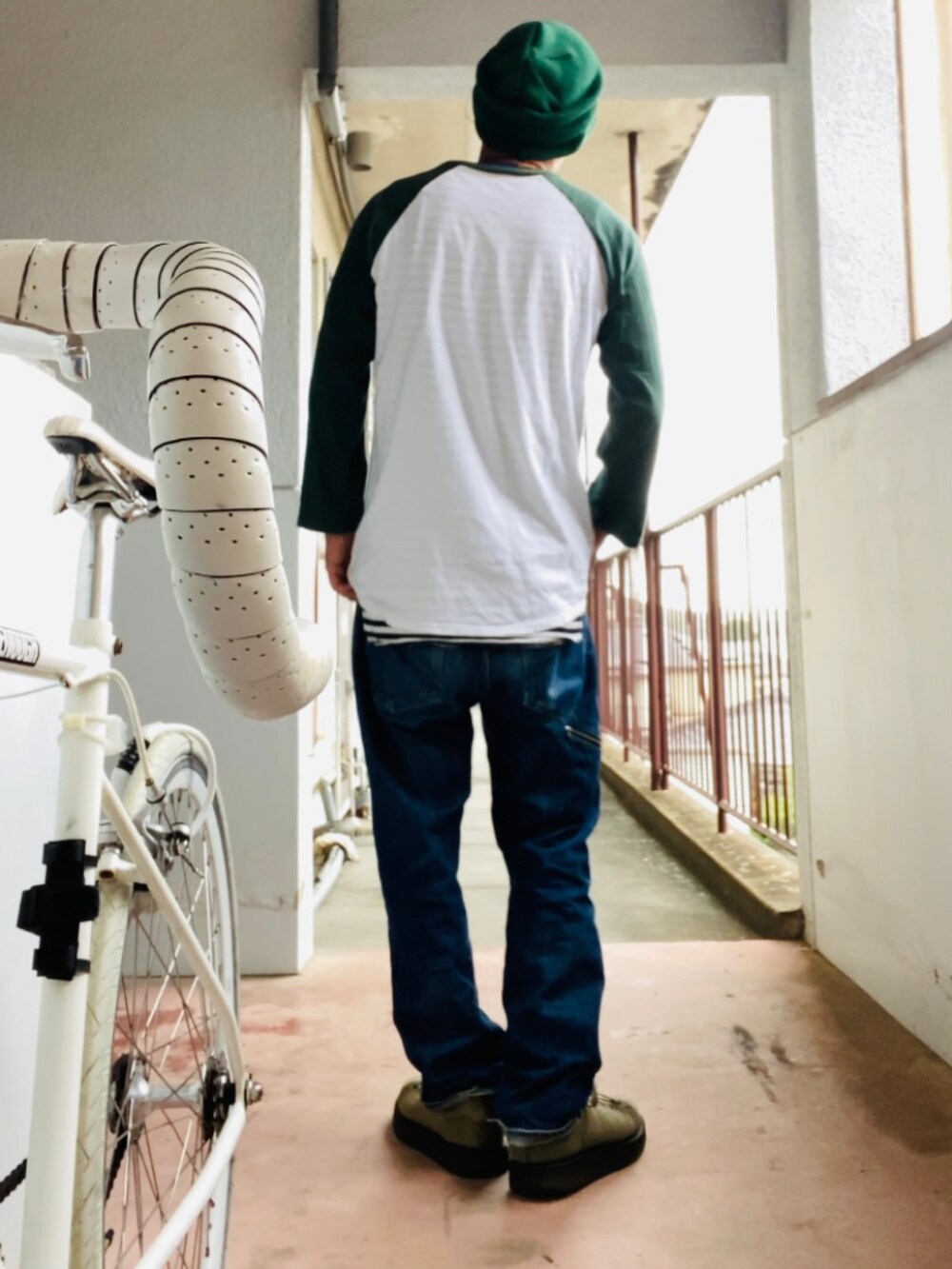 グリーン系のTシャツ/カットソー、ブルー系のデニムパンツ、グリーン系のスニーカーを着用したメンズの秋コーディネートの3枚目の写真