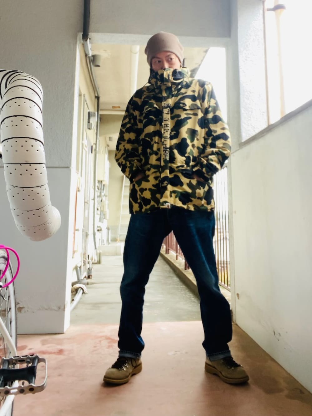 イエロー系のマウンテンパーカー、ブルー系のデニムパンツ、ベージュ系のブーツを着用したメンズの秋コーディネートの4枚目の写真