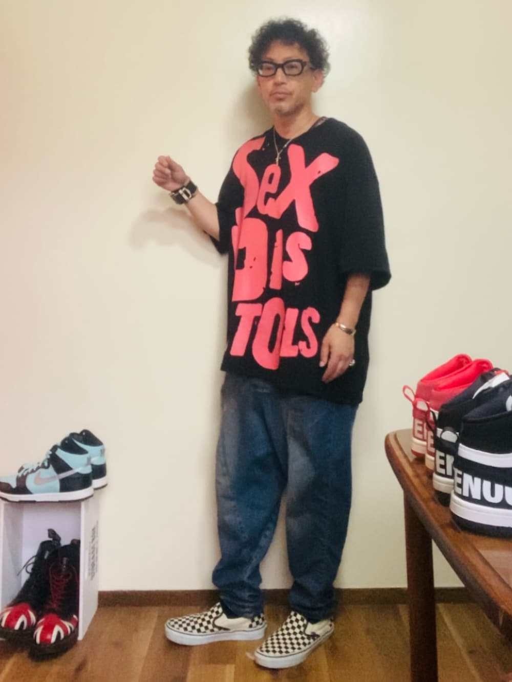 ブラック系のTシャツ/カットソー、ブルー系のデニムパンツ、ホワイト系のスリッポンを着用したメンズの夏コーディネートの2枚目の写真
