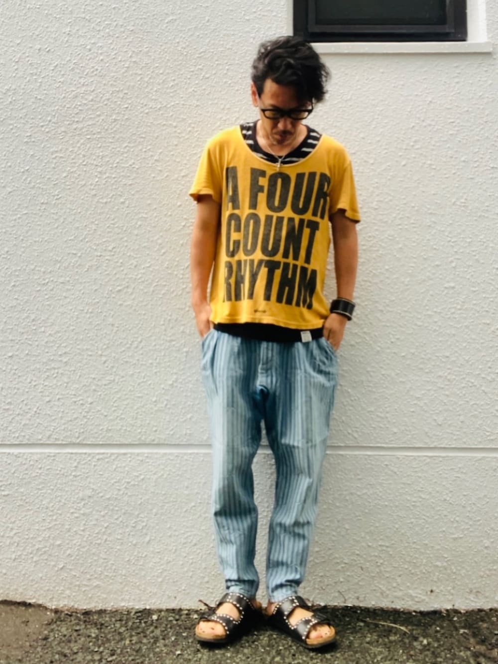 ゴールド系のTシャツ/カットソー、ブルー系のデニムパンツ、ブラック系のサンダルを着用したメンズの夏コーディネートの5枚目の写真