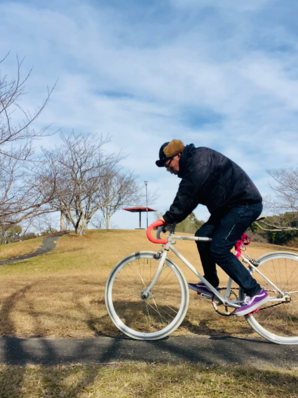 パープル系のスニーカー、ブラック系のマウンテンパーカー、ブルー系のデニムパンツを着用したメンズの冬コーディネートの3枚目の写真