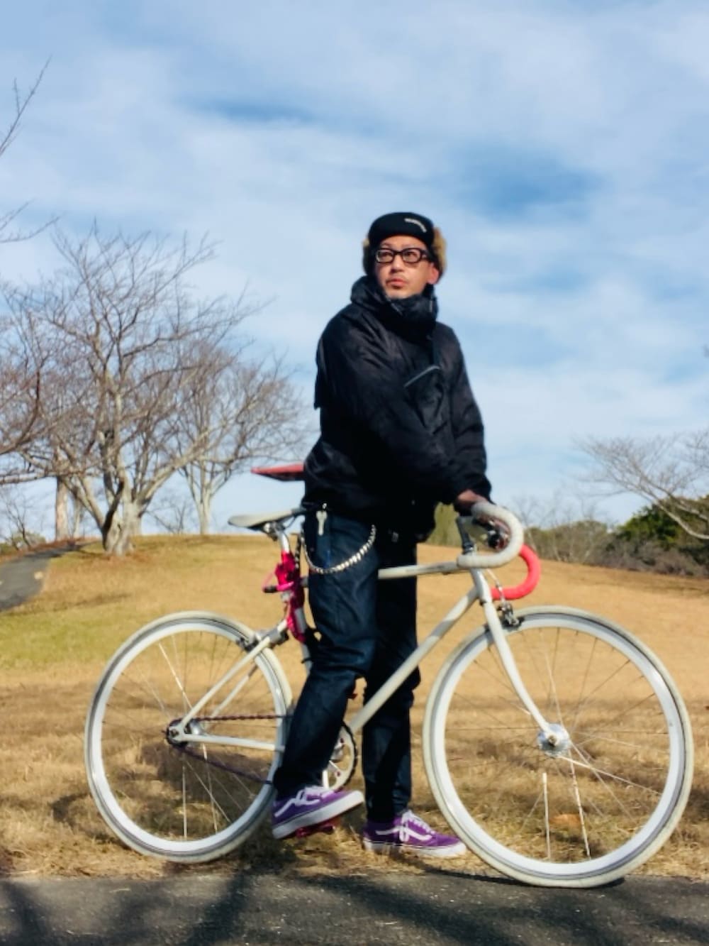 パープル系のスニーカー、ブラック系のマウンテンパーカー、ブルー系のデニムパンツを着用したメンズの冬コーディネートの4枚目の写真