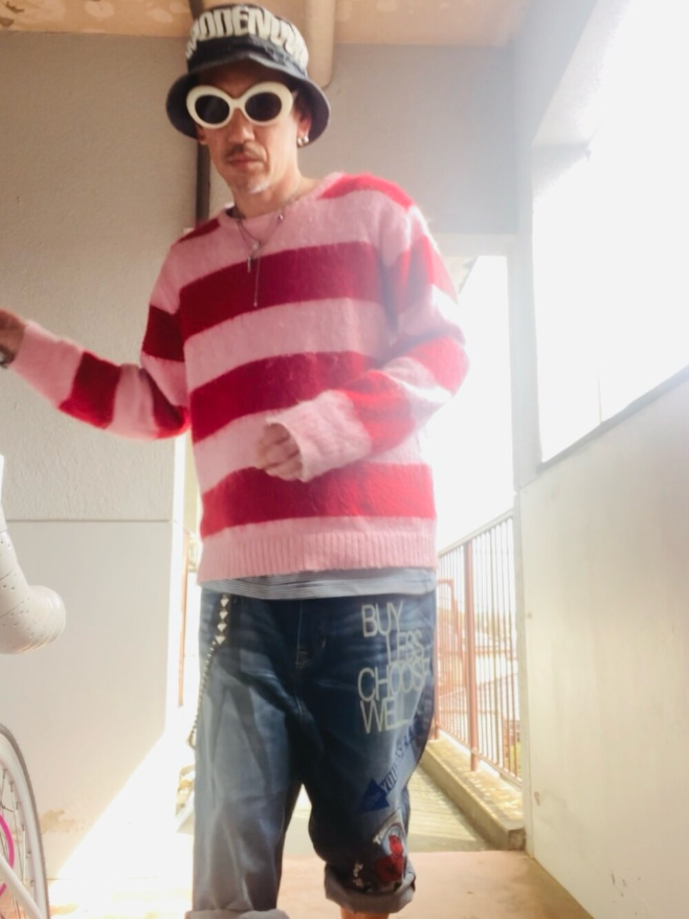 ブルー系のデニムパンツ、ピンク系のニット/セーター、ピンク系のスニーカーを着用したメンズの春コーディネートの4枚目の写真