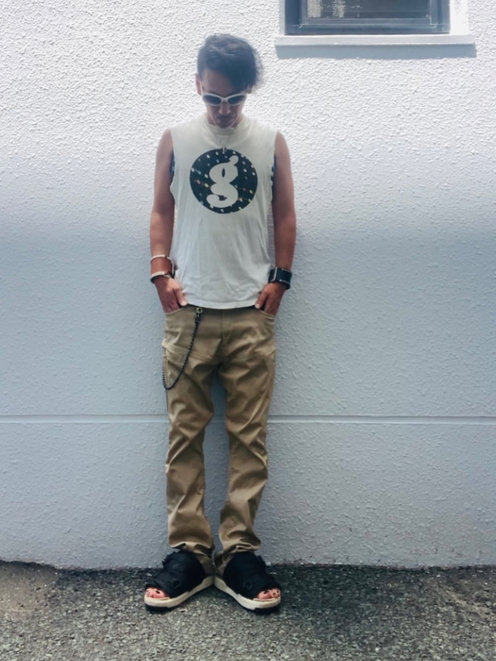 ホワイト系のTシャツ/カットソー、ベージュ系のチノパンツ、ブラック系のサンダルを着用したメンズの夏コーディネートの5枚目の写真