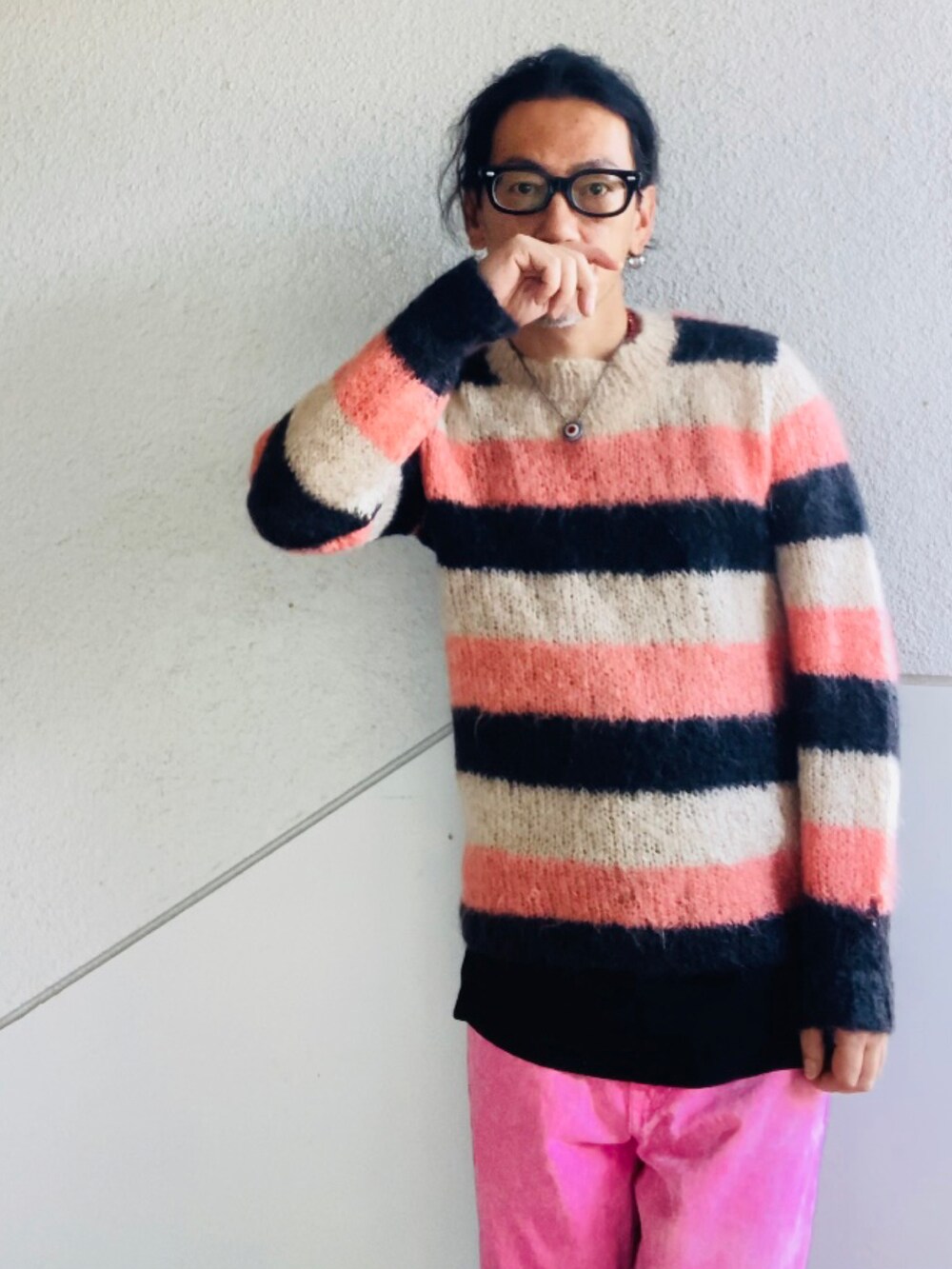 ピンク系のニット/セーター、ピンク系のデニムパンツ、ブラック系のスニーカーを着用したメンズの秋コーディネートの2枚目の写真