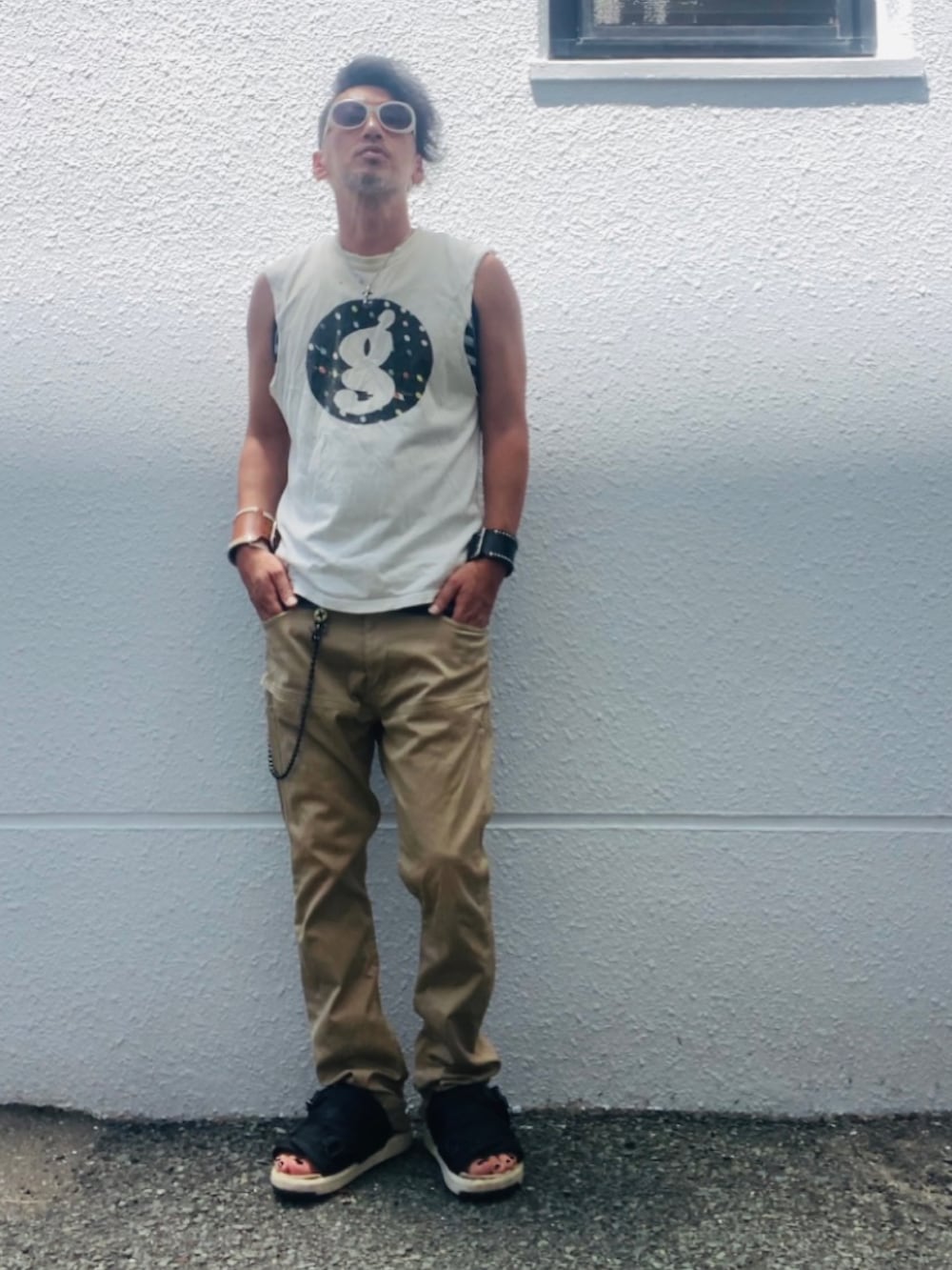 ホワイト系のTシャツ/カットソー、ベージュ系のチノパンツ、ブラック系のサンダルを着用したメンズの夏コーディネートの4枚目の写真