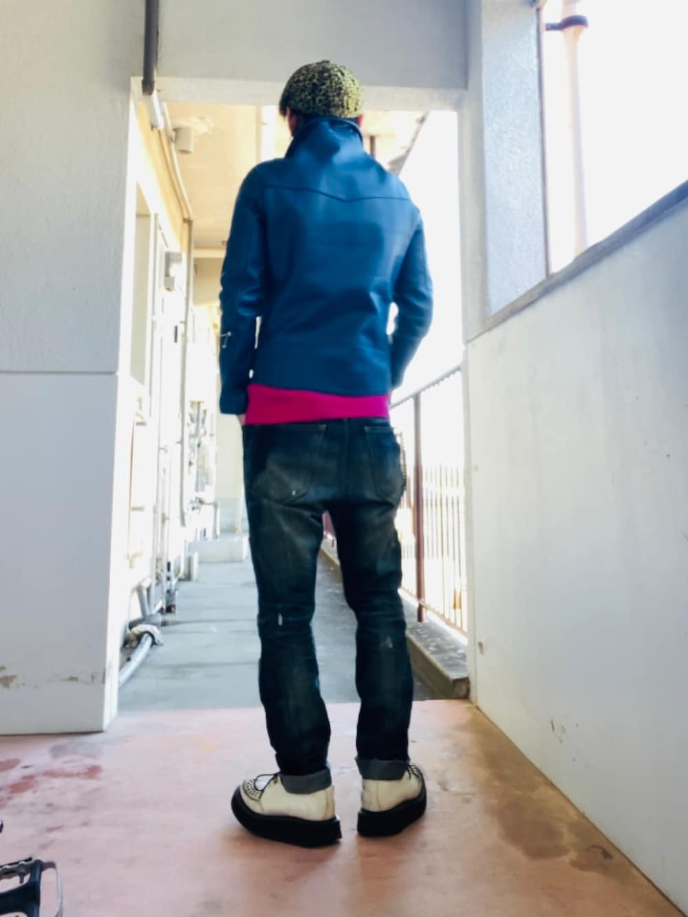 ブルー系のライダースジャケット、ピンク系のニット/セーター、ブルー系のデニムパンツを着用したメンズの冬コーディネートの4枚目の写真