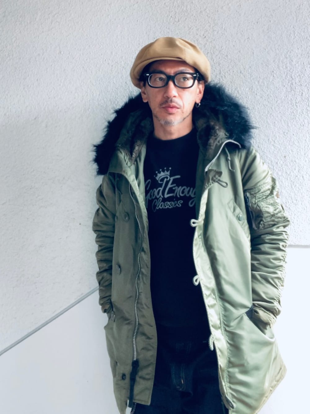 グリーン系のミリタリージャケット、ブラック系のスウェット、ブルー系のデニムパンツを着用したメンズの冬コーディネートの2枚目の写真