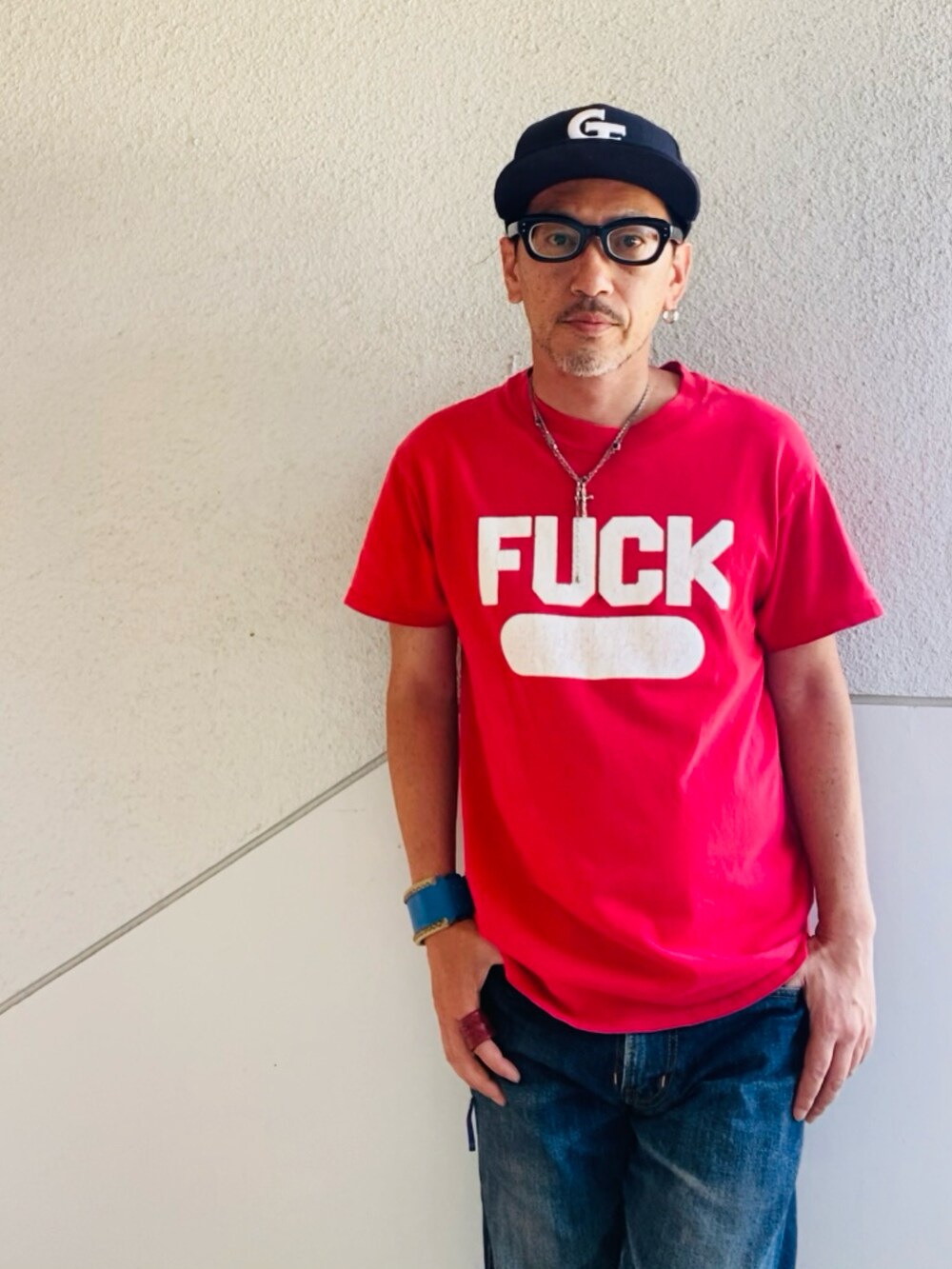 レッド系のTシャツ/カットソー、ブルー系のデニムパンツ、ブラック系のスニーカーを着用したメンズの夏コーディネートの3枚目の写真