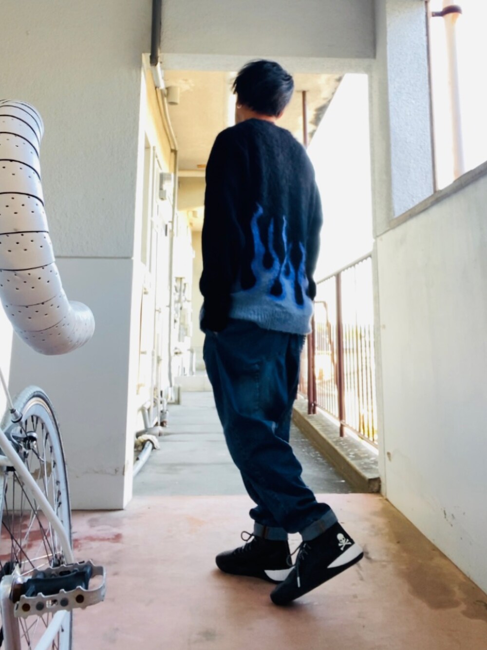 ブラック系のニット/セーター、ブルー系のデニムパンツ、ブラック系のスニーカーを着用したメンズの秋コーディネートの5枚目の写真