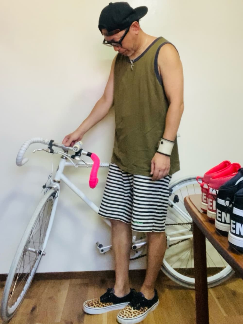 グリーン系のタンクトップ、グレー系のスウェットパンツ、ベージュ系のスニーカーを着用したメンズの夏コーディネートの3枚目の写真