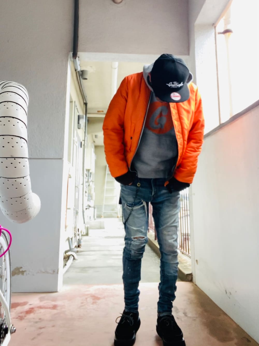 グレー系のパーカー、グレー系のMA-1、ブルー系のデニムパンツを着用したメンズの冬コーディネートの4枚目の写真