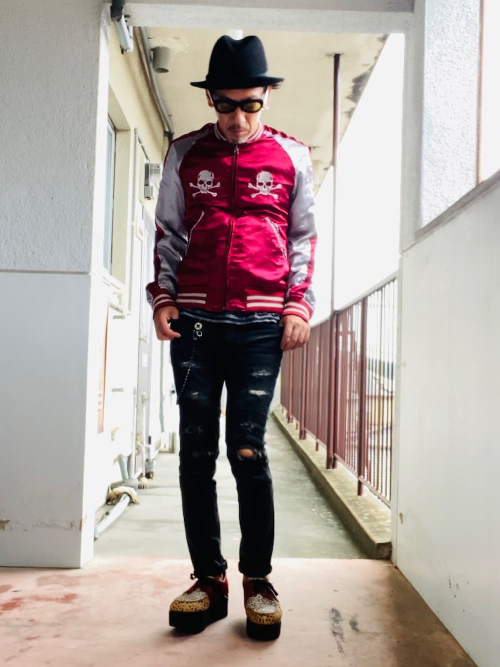 レッド系のスカジャン、ブラック系のタンクトップ、ブラック系のデニムパンツを着用したメンズの秋コーディネートの3枚目の写真