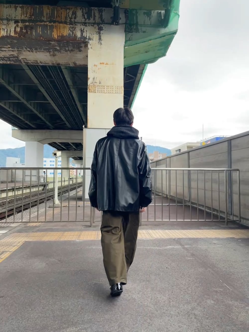 グレー系のニット/セーター、ブラック系のブルゾン、ブラウン系のチノパンツを着用したメンズの秋コーディネートの2枚目の写真