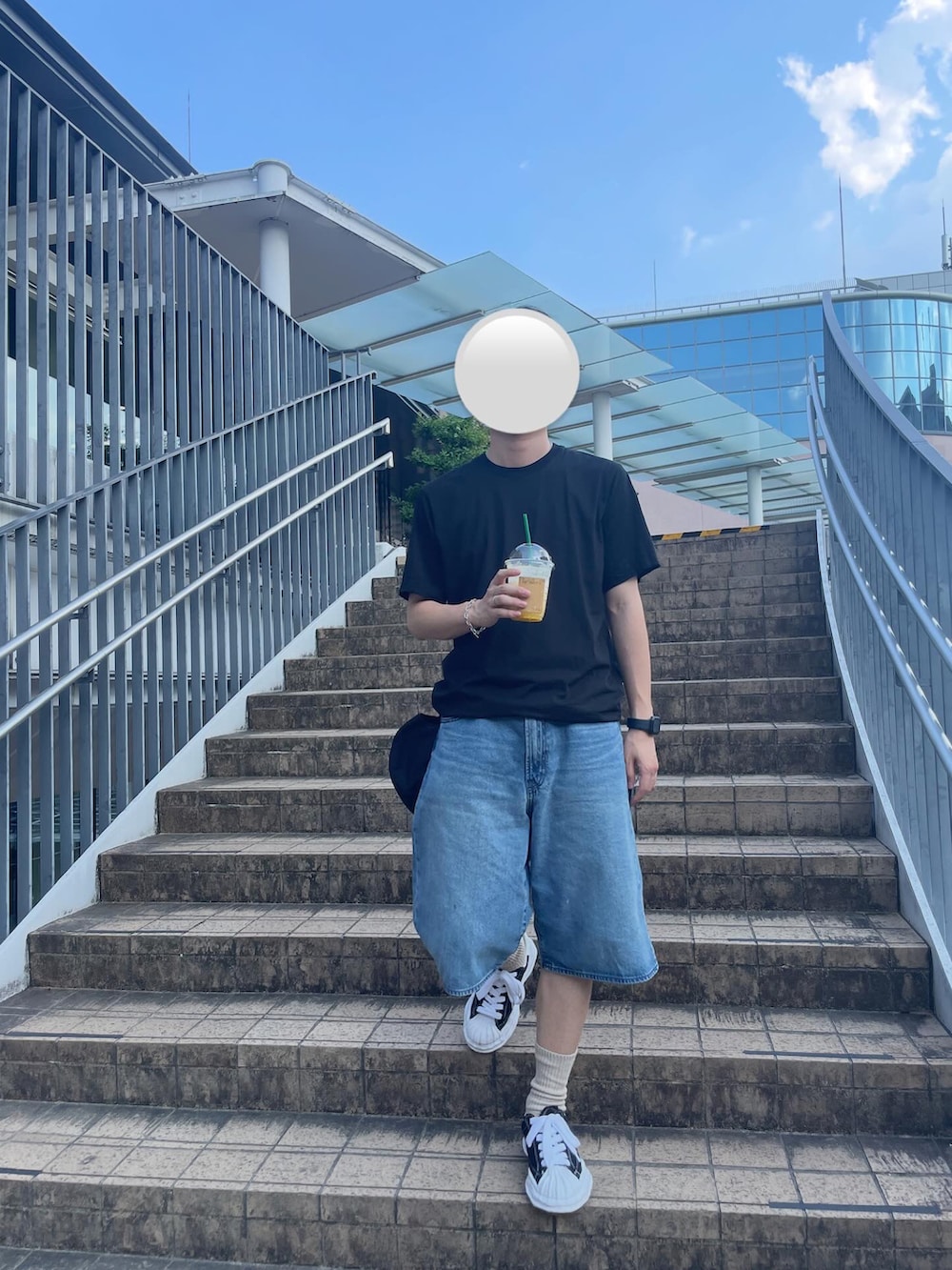 ブラック系のTシャツ/カットソー、ブルー系のデニムパンツ、ホワイト系のスニーカーを着用したメンズの秋コーディネートの2枚目の写真