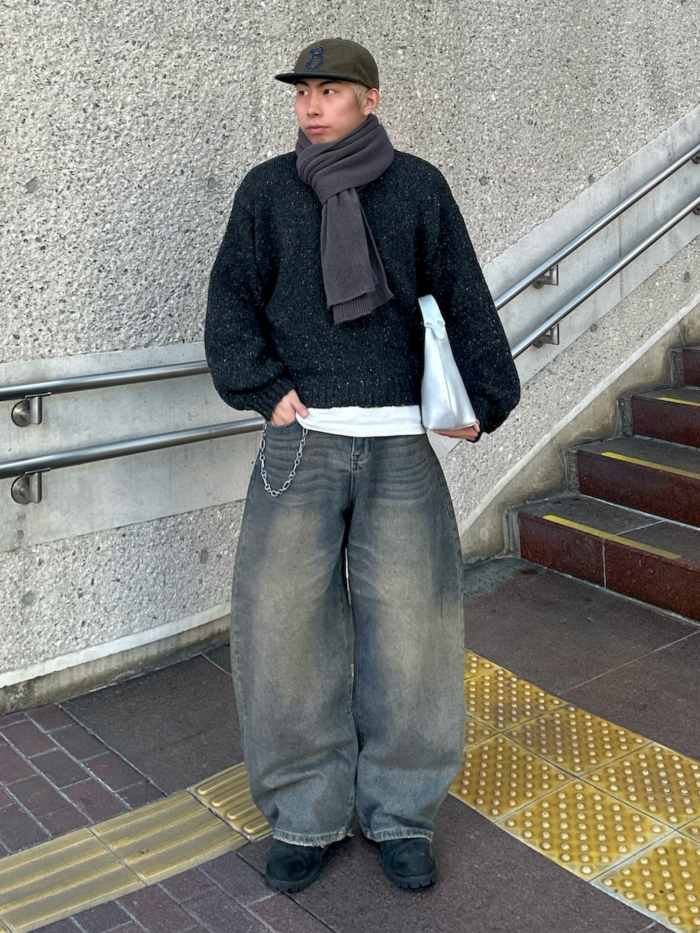 ブラック系のニット/セーター、ホワイト系のTシャツ/カットソー、ブルー系のデニムパンツを着用したメンズの冬コーディネートの2枚目の写真